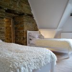 A twin room at Cotswold Manor that has a feature wall of exposed stone