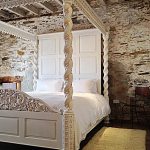 Ornate, carved, sumptuous 4 poster in the contemporary barn rooms at Devon Farmhouse, part of the The Big House Company