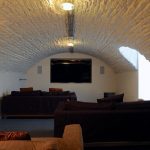 A party house with a lower ground floor cinema room, plenty of sofas and a wide screen for movies.