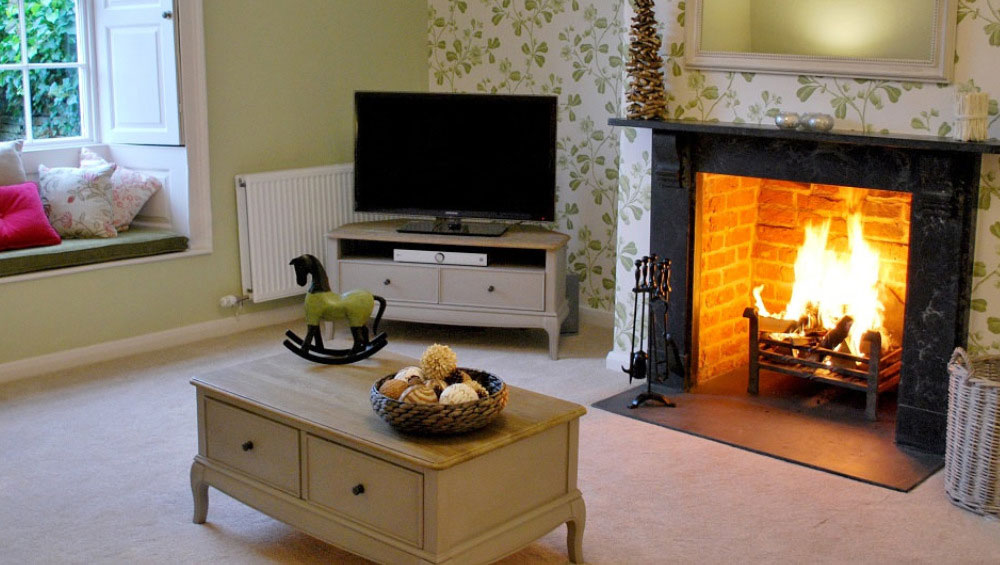 The sitting room with roaring log fire at Cotswold Manor available through The Big House Company