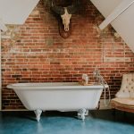 This bathroom has a roll top bath and attractive exposed brickwork.