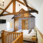 Exposed beams give this bedroom a cosy atmosphere at Tatham House in Somerset