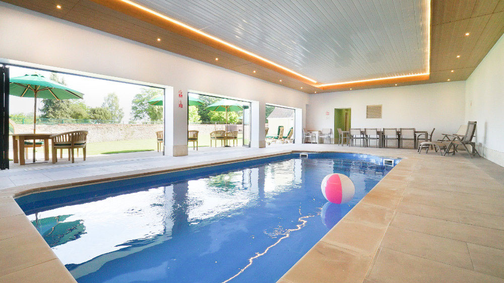 The indoor pool at Tatham House, Somerset with bi-fold doors out to the walled garden, terraces & seating