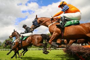 Race horses jumping over fences
