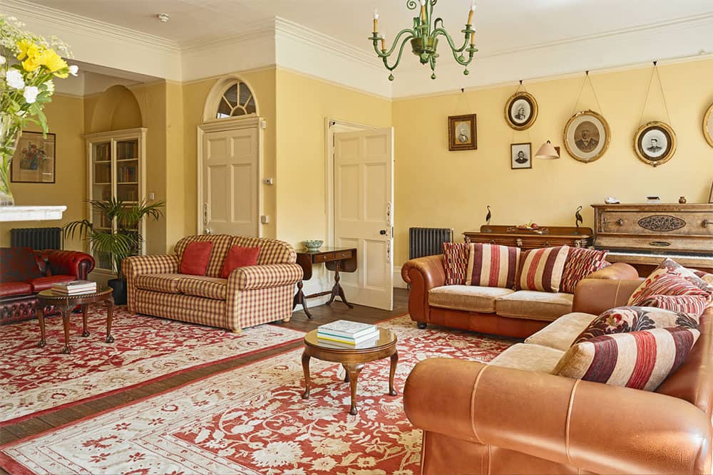 Traditional sitting room at Tatham House with large windows and fireplace.