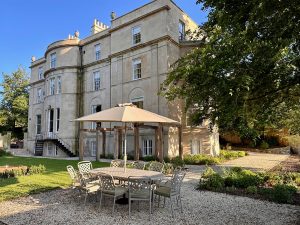 Outdoor dining area in the garden of Bath Villa with parasols, seating and the Georgian house in the background.