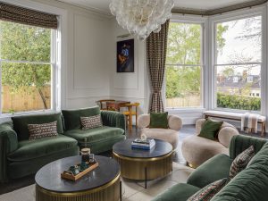Bright drawing room at Bath Villa with curved sofas, large windows and elegant chandeliers.