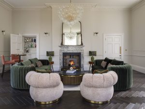 Stylish drawing room at Bath Villa featuring plush armchairs, a marble fireplace and soft neutral décor.