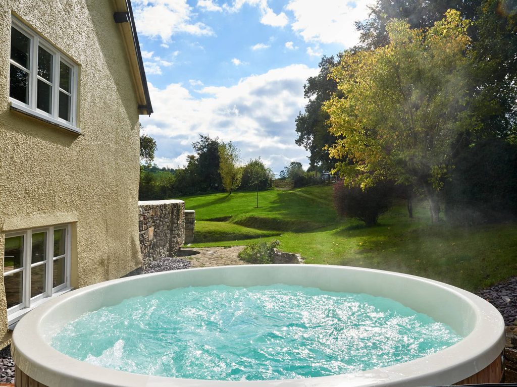 Outdoor hot tub at Bampton Longhouse in Devon with garden views — perfect for relaxing breaks, group getaways, and countryside escapes.
