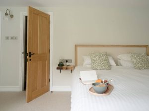 Peaceful double bedroom at Bampton Longhouse in Devon with a wooden headboard and breakfast tray