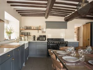 Stylish country kitchen at Bampton Longhouse in Devon with exposed beams, grey cabinetry, and a large range cooker.