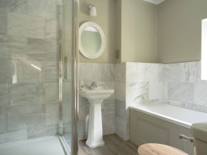 Modern bathroom at Bampton Longhouse in Devon with marble tiles, walk-in shower, and elegant traditional fittings
