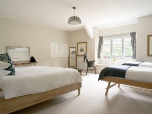 Light-filled family bedroom at Bampton Longhouse in Devon with double and twin beds, countryside views, and classic décor