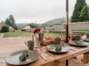 Outdoor dining at Bampton Longhouse in Devon with a beautifully set breakfast table overlooking rolling hills