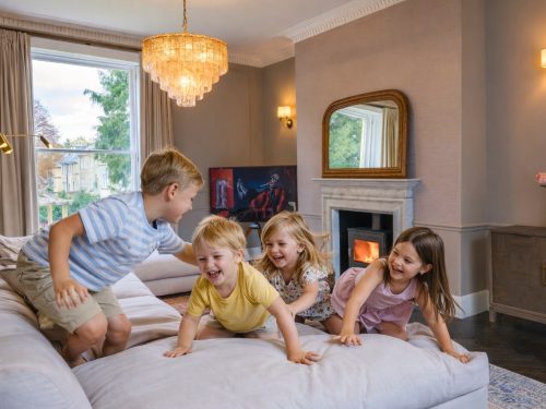 Children playing on a sofa in a cosy living room at a large country house.