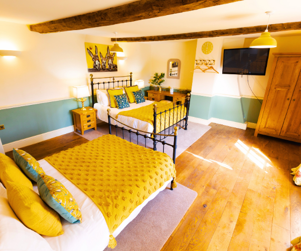 Multi-generational breaks in a Big House A big bedroom with beams, wooden floor and two large beds, with yellow bedding