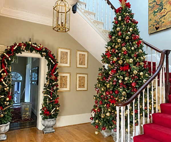 Christmas tree on the staircase at Somerset Manor, with a red and gold garland arch